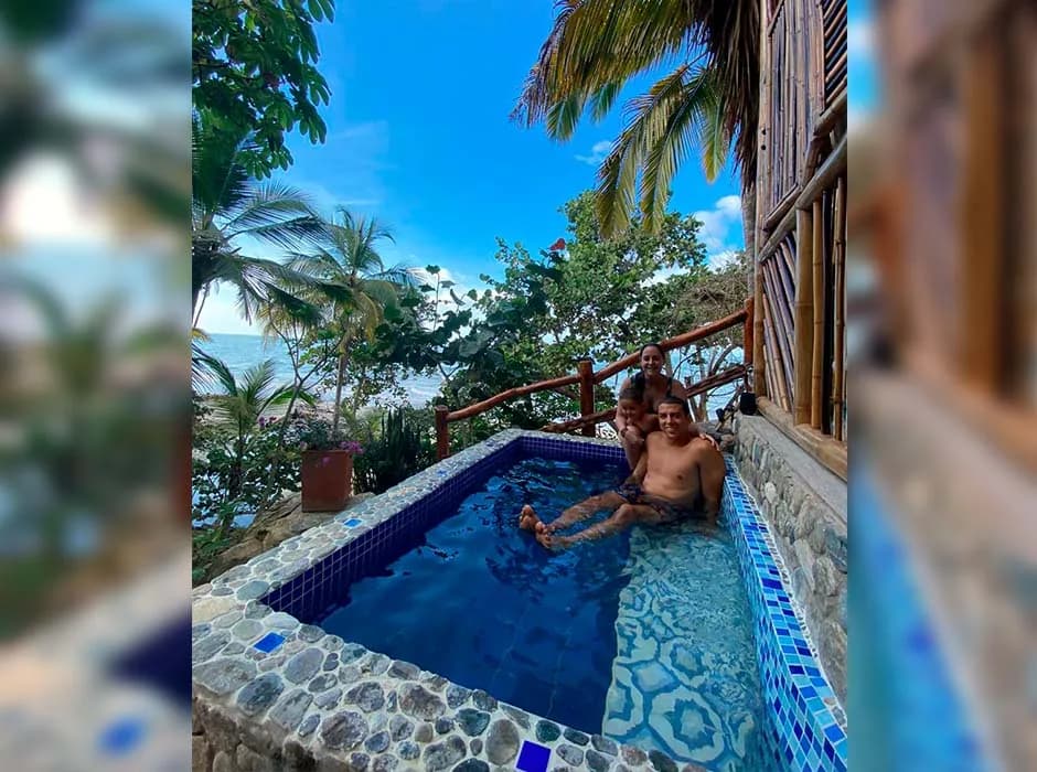 Piscina de agua clara junto a la cabaña, rodeada de palmeras